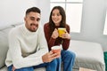 Young hispanic couple drinking coffee sitting on the sofa at home Royalty Free Stock Photo