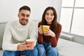 Young hispanic couple drinking coffee sitting on the sofa at home Royalty Free Stock Photo