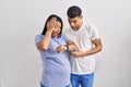 Young hispanic couple expecting a baby standing over background looking at the watch time worried, afraid of getting late