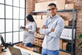 Young hispanic couple expecting a baby working at small business ecommerce looking positive and happy standing and smiling with a Royalty Free Stock Photo