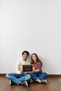 Young hispanic couple holding our first home blackboard sitting on the floor at empty new house Royalty Free Stock Photo