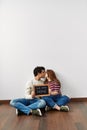 Young hispanic couple holding our first home blackboard sitting on the floor at empty new house Royalty Free Stock Photo