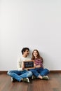 Young hispanic couple holding our first home blackboard sitting on the floor at empty new house Royalty Free Stock Photo