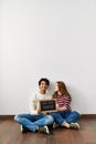 Young hispanic couple holding our first home blackboard sitting on the floor at empty new house Royalty Free Stock Photo