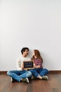 Young hispanic couple holding our first home blackboard sitting on the floor at empty new house Royalty Free Stock Photo