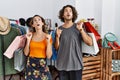 Young hispanic couple holding shopping bags at retail shop amazed and surprised looking up and pointing with fingers and raised Royalty Free Stock Photo