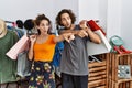 Young hispanic couple holding shopping bags at retail shop pointing with finger surprised ahead, open mouth amazed expression, Royalty Free Stock Photo