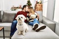 Young hispanic couple kissing and watching movie sitting on the sofa with dog at home Royalty Free Stock Photo