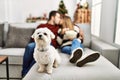 Young hispanic couple kissing and watching movie sitting on the sofa with dog at home Royalty Free Stock Photo