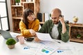 Young hispanic couple with serious expression using laptop and smartphone sitting on the table at home Royalty Free Stock Photo