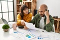 Young hispanic couple with serious expression using laptop and smartphone sitting on the table at home Royalty Free Stock Photo