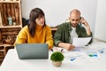 Young hispanic couple with serious expression using laptop and smartphone sitting on the table at home Royalty Free Stock Photo