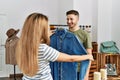 Young hispanic couple smiling happy choosing clothes at clothing store