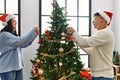 Young hispanic couple smiling happy decorating christmas tree at home