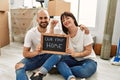 Young hispanic couple smiling happy holding our new home blackboard and key at new home Royalty Free Stock Photo