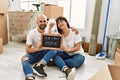Young hispanic couple smiling happy holding our new home blackboard and key at new home Royalty Free Stock Photo