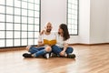 Young hispanic couple smiling happy reading book at empty new home Royalty Free Stock Photo