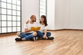 Young hispanic couple smiling happy reading book at empty new home Royalty Free Stock Photo