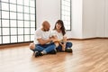 Young hispanic couple smiling happy reading book at empty new home Royalty Free Stock Photo