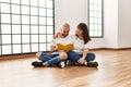 Young hispanic couple smiling happy reading book at empty new home Royalty Free Stock Photo