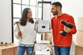 Young hispanic couple smiling happy repairing new home