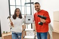Young hispanic couple smiling happy repairing new home