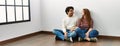 Young hispanic couple smiling happy sitting on the floor at empty new home Royalty Free Stock Photo