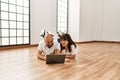 Young hispanic couple smiling happy using laptop at empty new home Royalty Free Stock Photo