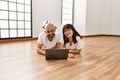 Young hispanic couple smiling happy using laptop at empty new home Royalty Free Stock Photo