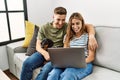 Young hispanic couple smiling happy using laptop sitting on the sofa  with dog at home Royalty Free Stock Photo