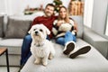 Young hispanic couple smiling happy watching movie sitting on the sofa with dog at home
