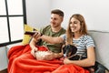 Young hispanic couple smiling happy watching movie sitting on the sofa with dog at home Royalty Free Stock Photo