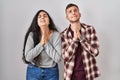 Young hispanic couple standing over white background begging and praying with hands together with hope expression on face very Royalty Free Stock Photo