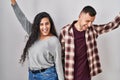 Young hispanic couple standing over white background dancing happy and cheerful, smiling moving casual and confident listening to Royalty Free Stock Photo