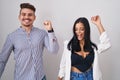 Young hispanic couple standing over white background dancing happy and cheerful, smiling moving casual and confident listening to Royalty Free Stock Photo