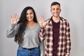 Young hispanic couple standing over white background showing and pointing up with fingers number ten while smiling confident and Royalty Free Stock Photo