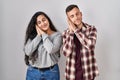 Young hispanic couple standing over white background sleeping tired dreaming and posing with hands together while smiling with Royalty Free Stock Photo