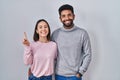 Young hispanic couple standing together showing and pointing up with finger number one while smiling confident and happy Royalty Free Stock Photo