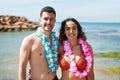 Young hispanic couple tourists wearing hawaiian lei hugging each other at seaside Royalty Free Stock Photo