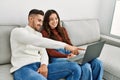 Young hispanic couple using laptop sitting on the sofa at home Royalty Free Stock Photo