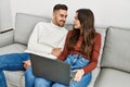Young hispanic couple using laptop sitting on the sofa at home Royalty Free Stock Photo