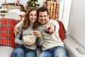Young hispanic couple watching movie and eating popcorn sitting on the sofa at home Royalty Free Stock Photo