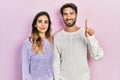 Young hispanic couple wearing casual clothes showing and pointing up with finger number one while smiling confident and happy Royalty Free Stock Photo