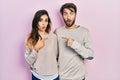 Young hispanic couple wearing casual clothes surprised pointing with finger to the side, open mouth amazed expression Royalty Free Stock Photo