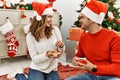 Young hispanic couple wearing christmas hat drinking coffee and eating cookies at home Royalty Free Stock Photo