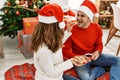 Young hispanic couple wearing christmas hat drinking coffee and eating cookies at home Royalty Free Stock Photo