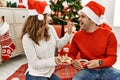 Young hispanic couple wearing christmas hat drinking coffee and eating cookies at home Royalty Free Stock Photo