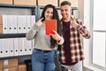 Young hispanic couple working at small business ecommerce doing video call smiling happy pointing with hand and finger Royalty Free Stock Photo