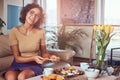 Young Hispanic curly girl having breakfast at home sitting on the sofa. Royalty Free Stock Photo