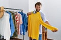 Young hispanic customer man smiling happy choosing clothes at clothing store